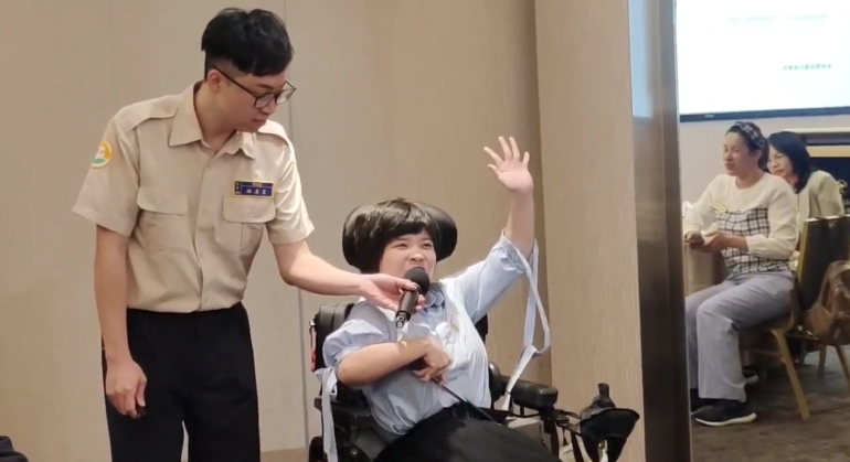 《圖說》八里愛心教養院院生翁彥如在替代役男林嘉宏(左)的熱心協助下，到台北民樂扶輪社例會中演講。〈社會局提供〉